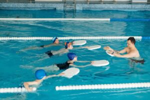 A coach teaching 4 kids how to swim