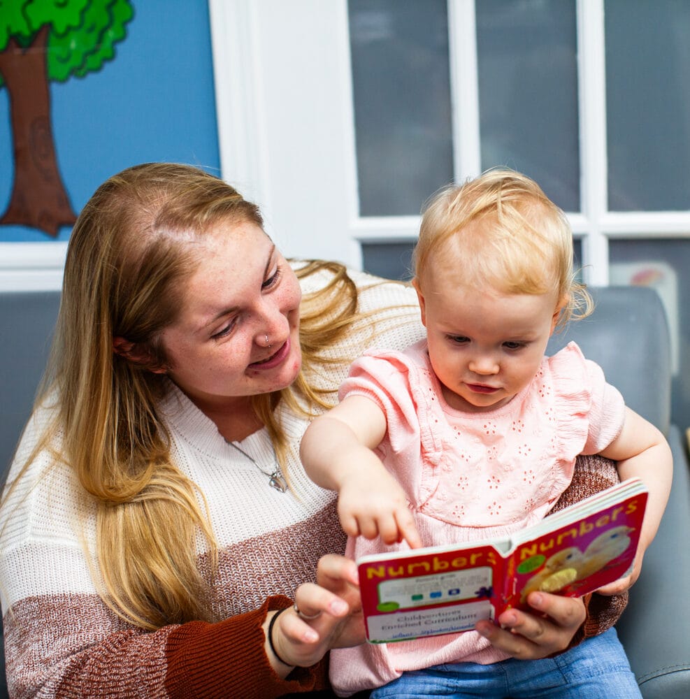Lady with toddler in lap reading a book