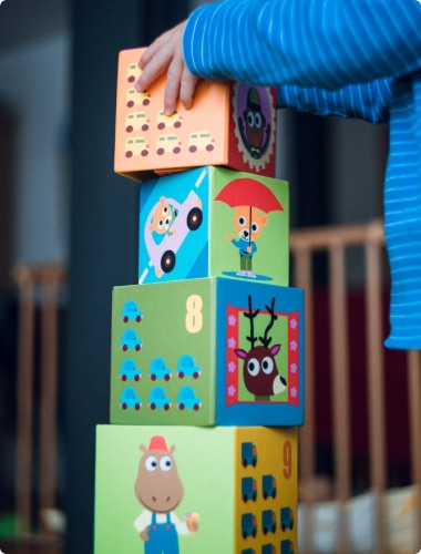 Child stacking toy blocks with numbers and animal drawings
