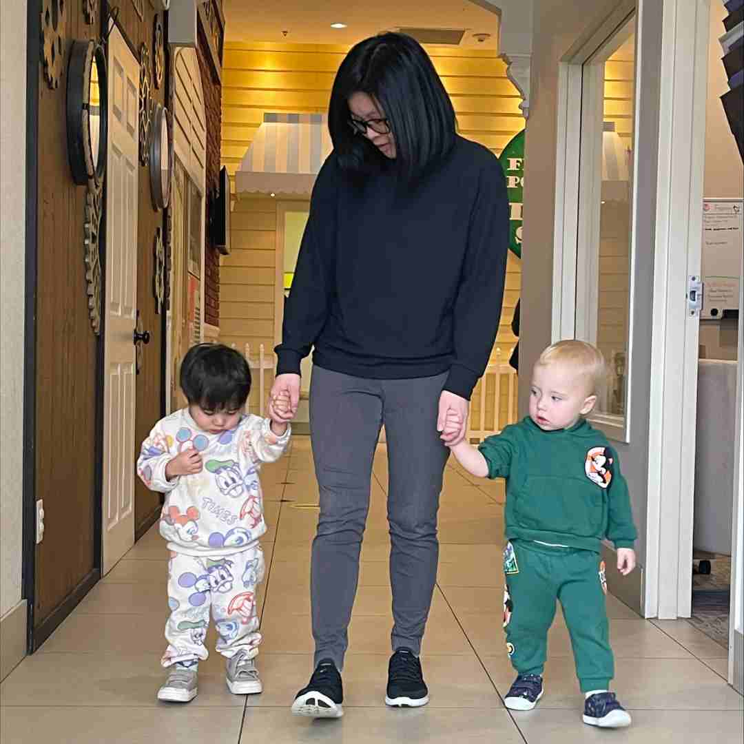lady holding two little boys' hands as they walk