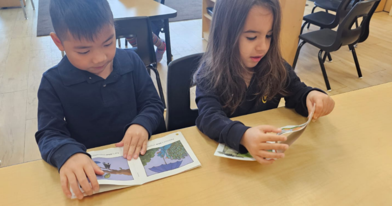 Boy and girl sitting at a desk and reading stories